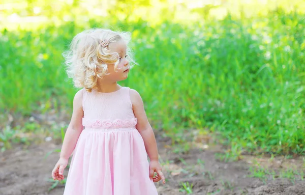 Roztomilé malé dítě dívka s kudrnatými vlasy, na sobě růžové šaty v p — Stock fotografie