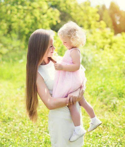 Liebevolle Mutter hält an Händen Kind umarmt im Sommertag — Stockfoto