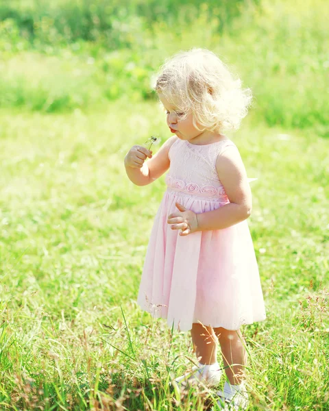 Little girl child blowing dandelion flower in spring field — Stock Photo, Image