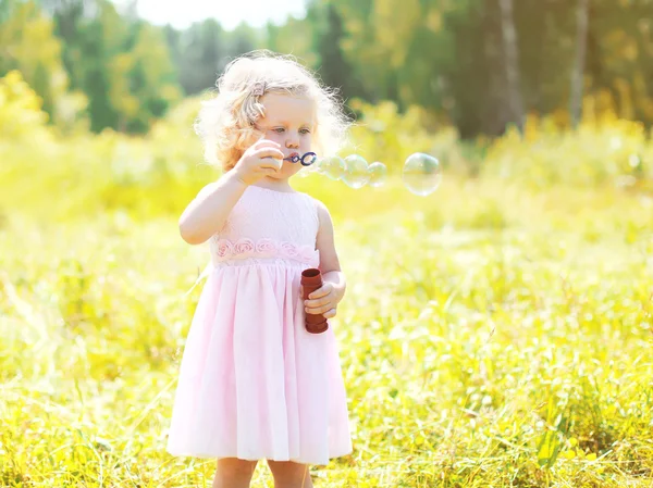 Sabun köpüğü güneşli yaz günde üfleyen küçük kız çocuk — Stok fotoğraf