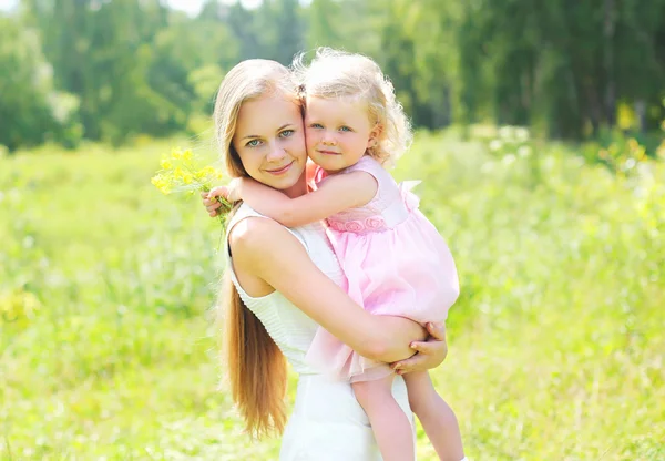 Mother holding on hands child hugging in summer day — Stock Photo, Image