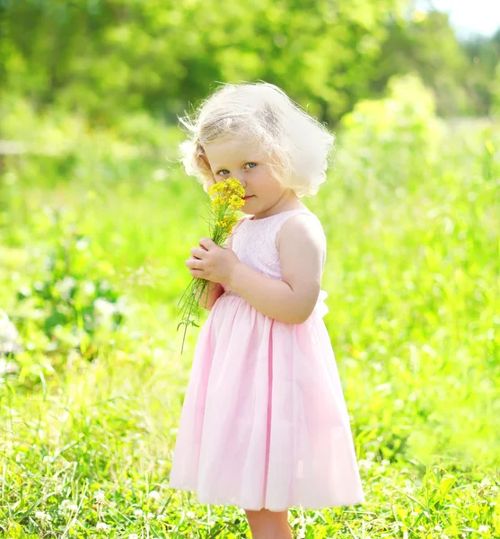 Portre küçük kız çocuğu ile bahar tarlada çiçekler — Stok fotoğraf