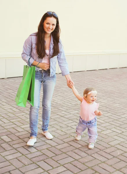Mãe feliz e bebê com sacos de compras andando na cidade — Fotografia de Stock