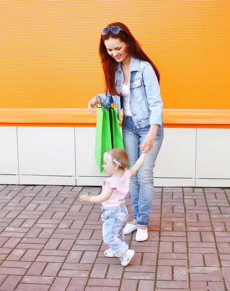 Feliz mamá y bebé con bolsas de compras caminando en la ciudad —  Fotos de Stock