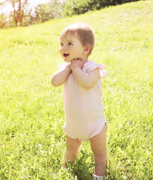 Feliz bebê sorrindo em pé na grama no dia ensolarado de verão — Fotografia de Stock