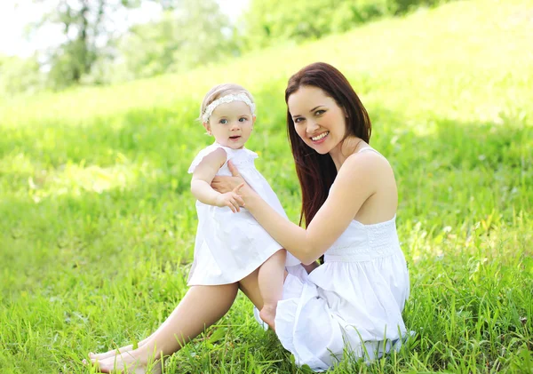 Anne ve bebek güneşli summ çimlere oturup gülümseyen mutlu
