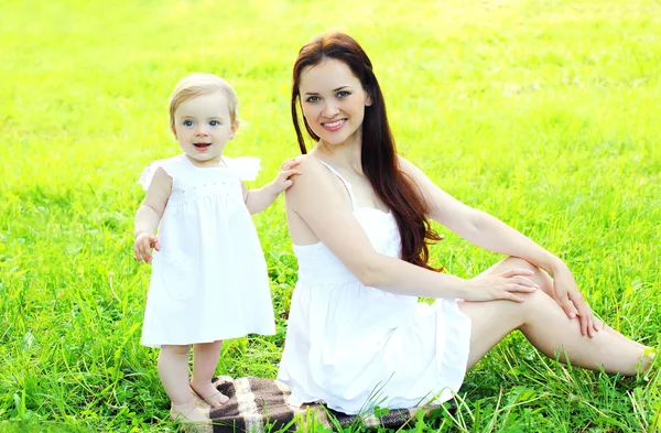 Happy smiling mother and child on the grass in sunny summer day — Stock Photo, Image