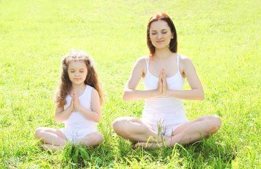 Anne ve çocuk çim üzerinde meditasyon yoga yaparken lotus poz