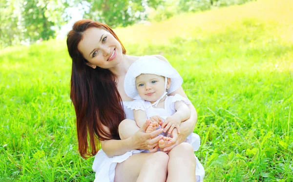 Gelukkig lachend moeder met baby op het gras in zomerdag — Stockfoto