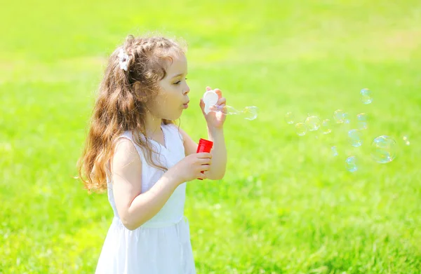 Lilla flickan barnet blåser såpbubblor i soliga sommardag — Stockfoto