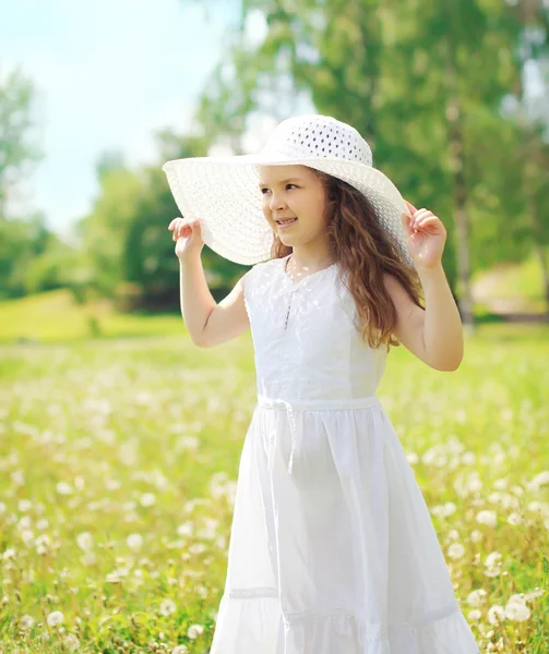 Niña pequeña con sombrero de paja y vestido blanco en verano — Foto de Stock