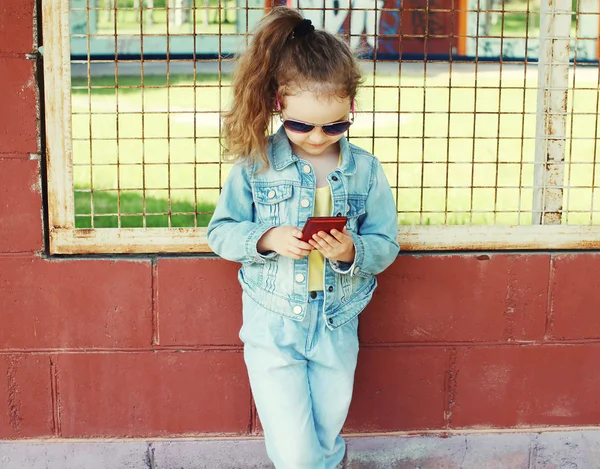 Little girl using smartphone, stylish child wearing a jeans clot — Stock Photo, Image