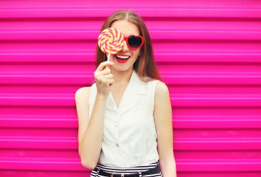 Lolipop ile eğleniyor pembe arkaya tatlı genç ve güzel kadın