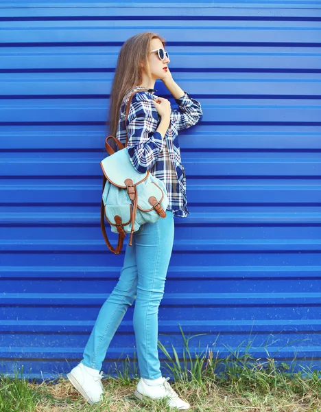 Fashion pretty girl wearing a plaid shirt with backpack over blu — Stock Photo, Image