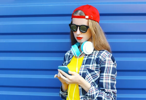 Pretty cool girl listens to music in headphones and using smartp — Stock Photo, Image