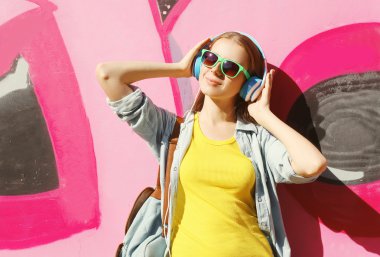 Pretty cool girl wearing a sunglasses, headphones and skateboard