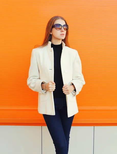 Fashion pretty woman wearing a white coat jacket against orange — Stock fotografie