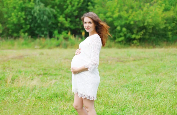 Красивая молодая беременная женщина в платье на природе — стоковое фото