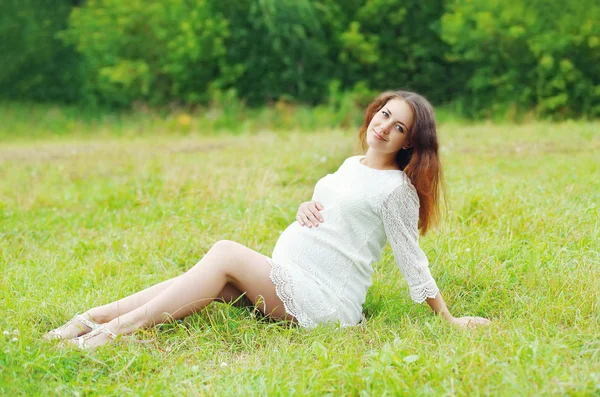 Beautiful young pregnant woman lying on grass summer — Stok fotoğraf