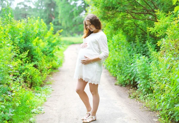 Beautiful young pregnant woman in white dress outdoors on nature — Stock Photo, Image