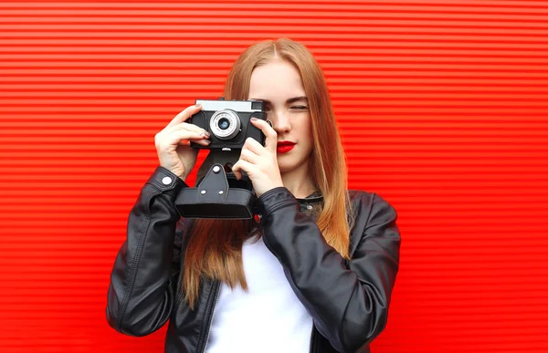 Fashion pretty woman with old retro camera over red background — Stock fotografie