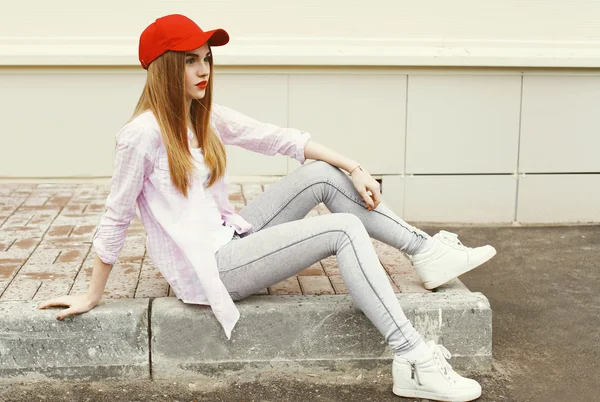 Модная симпатичная девушка в рубашке и красной кепке на улице — стоковое фото