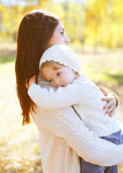 Feliz madre cariñosa abrazando al niño en otoño cálido día —  Fotos de Stock