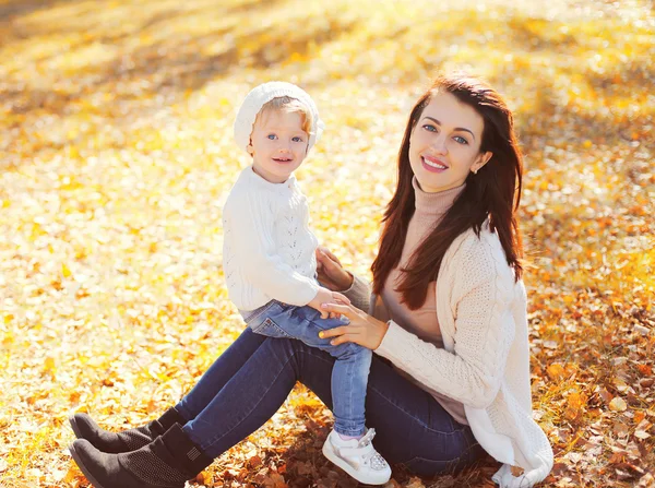 Bonne maman souriante avec un petit enfant jouant dans un parc d'automne ensoleillé — Photo