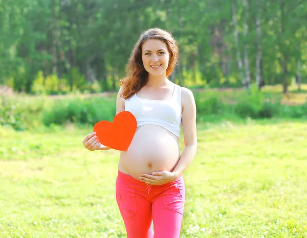 Happy smiling young pregnant woman showing big paper heart shape Royalty Free Stock Images