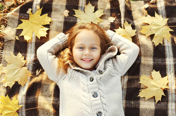 Portrait happy smiling child lying on plaid with yellow maple le — Stock Photo, Image