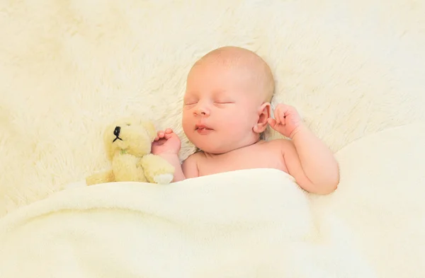 Cute infant sleeping together with teddy bear toy on the bed at — Stock Photo, Image