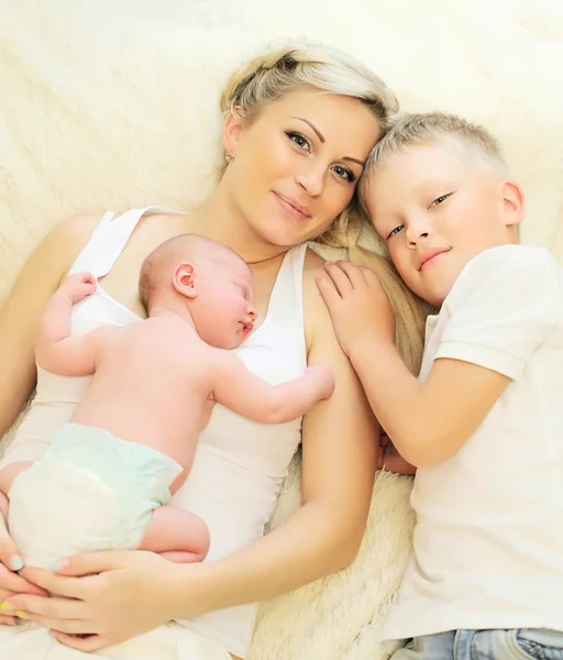 Glückliche Mutter mit zwei Kindern, die zu Hause zusammen im Bett schlafen — Stockfoto