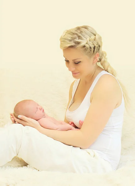 Feliz sonriente madre sosteniendo en manos durmiendo bebé en casa —  Fotos de Stock