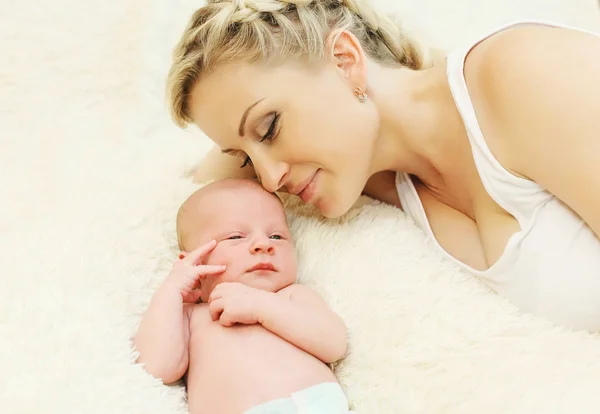 Glücklich lächelnde Mutter mit Baby, das zu Hause zusammen im Bett liegt — Stockfoto