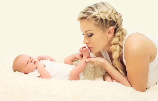 Madre cariñosa besando pies bebé en la cama en casa —  Fotos de Stock