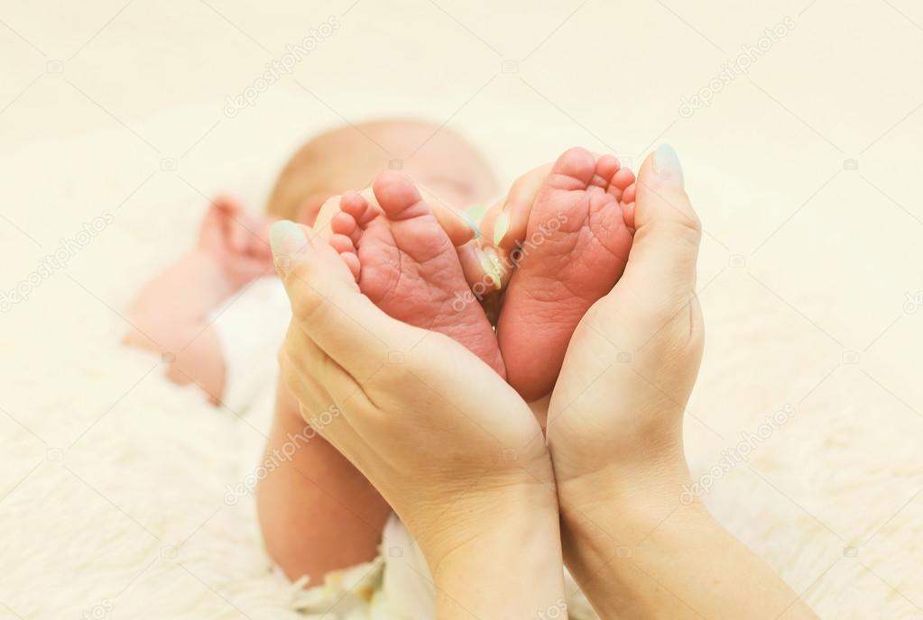 Baby feet in shape heart closeup at home