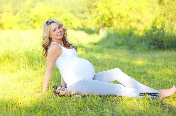 Feliz mujer embarazada sonriente al aire libre en la hierba en verano soleado d — Foto de Stock