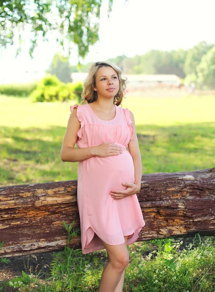 Velmi těhotná žena v růžových šatech venku v přírodě — Stock fotografie