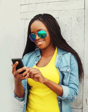 Beautiful smiling african woman using smartphone in city