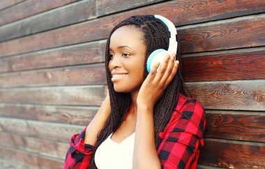 Güzel gülümseyen Afrikalı kadın kulaklık ile müzik dinliyor