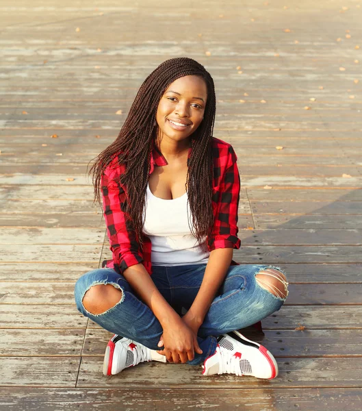 Schöne junge lächelnde Afrikanerin sitzt ausgeruht in der Stadt — Stockfoto
