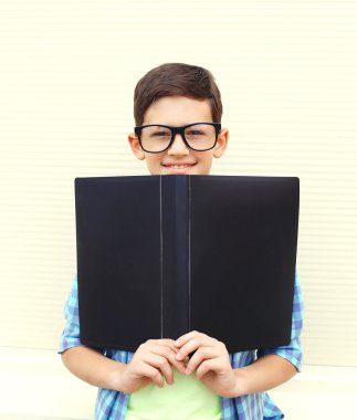 Portrait smiling smart teenager boy in glasses with folder or bo