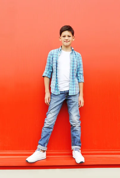 Hermoso niño con una camisa a cuadros y jeans en la ciudad —  Fotos de Stock