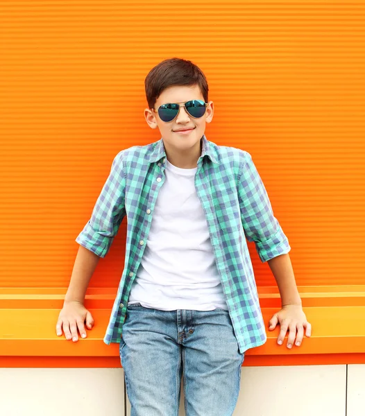 Stylish teenager boy wearing a checkered shirt and sunglasses wi