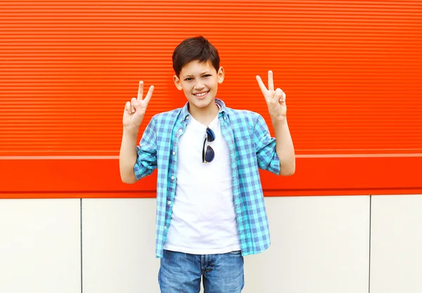 Cool smiling child boy having fun in city over red background — Stock fotografie