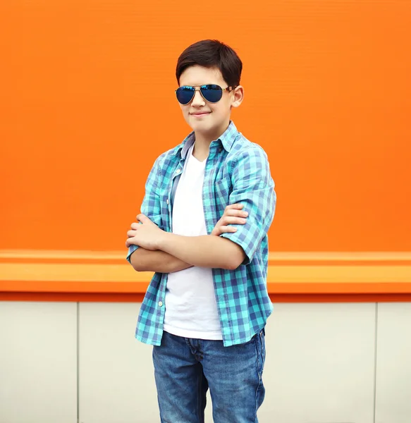 Moda criança menino vestindo um óculos de sol e camisa na cidade mais ou — Fotografia de Stock