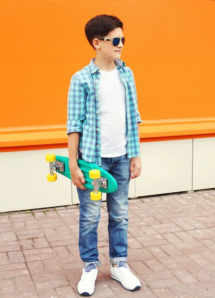 Fashion child boy wearing a sunglasses and shirt in city against