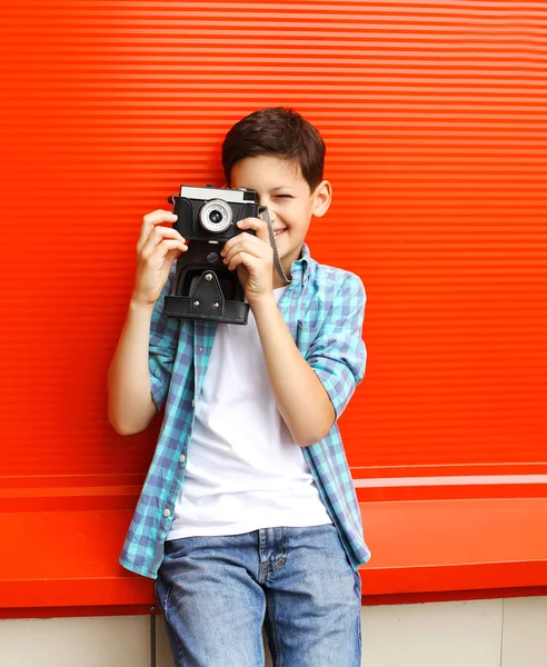 Happy little boy teenager with retro vintage camera in city over — Stock fotografie