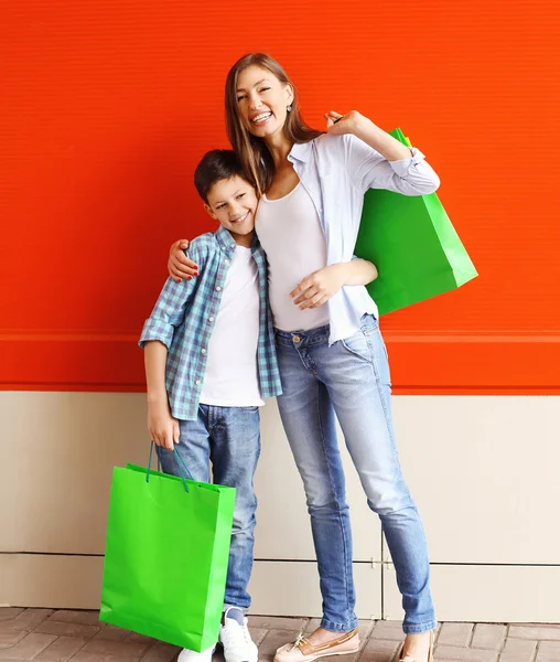 Happy smiling mother and son child with shopping bags having fun