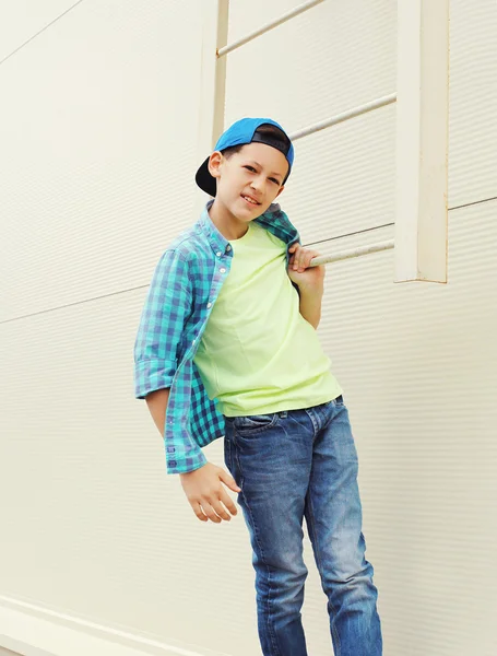 Stylish child boy wearing a shirt and baseball cap in city — ストック写真